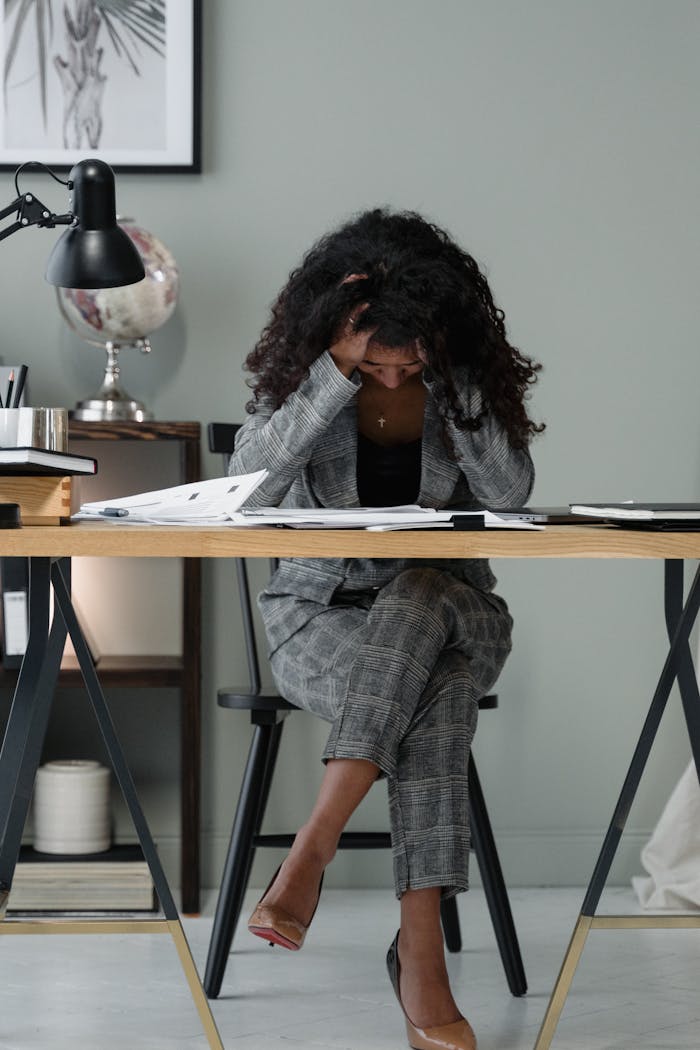 Teenused A frustrated businesswoman sitting at a desk, stressed in a modern office setting.