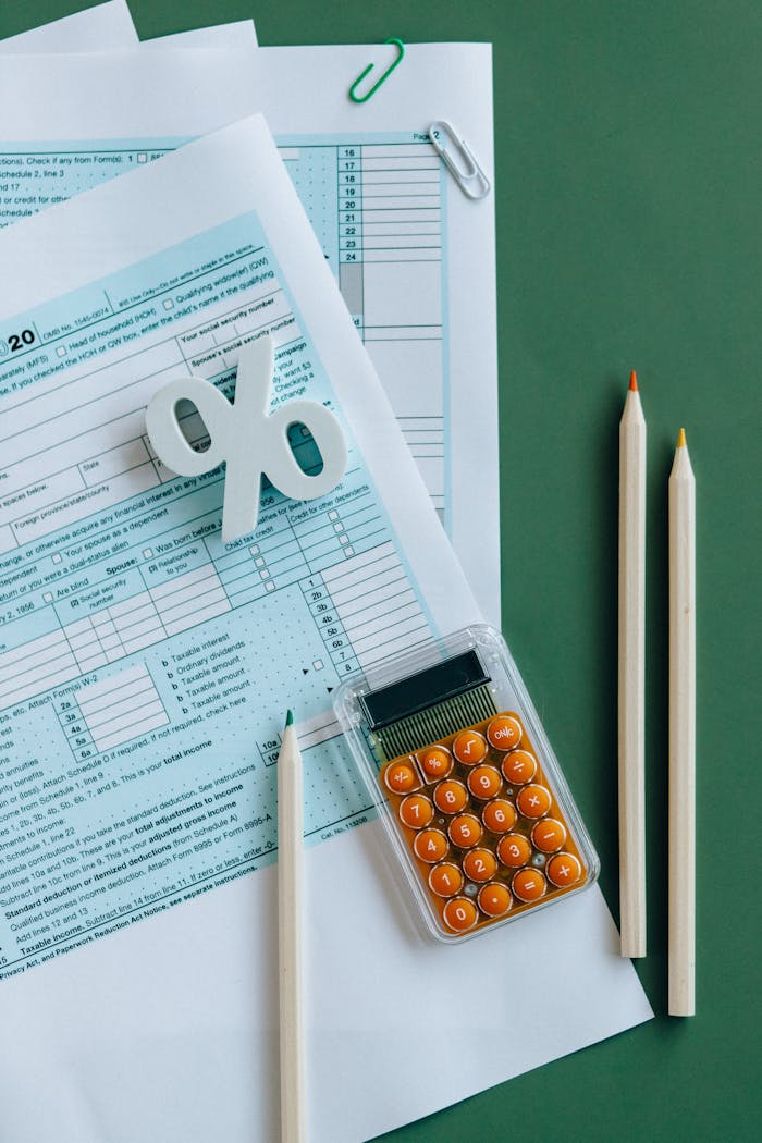 Teenused Flat lay of tax documents, calculator, and pencils on green surface.